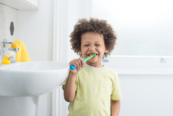 Happy kid brushes his teeth using Benjamin Brush and the pom pom head for toddlers