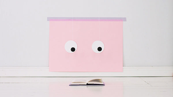 Pink rectangle head with goggly eyes reads magazine by Lucas Zanotto - part of Eyes project